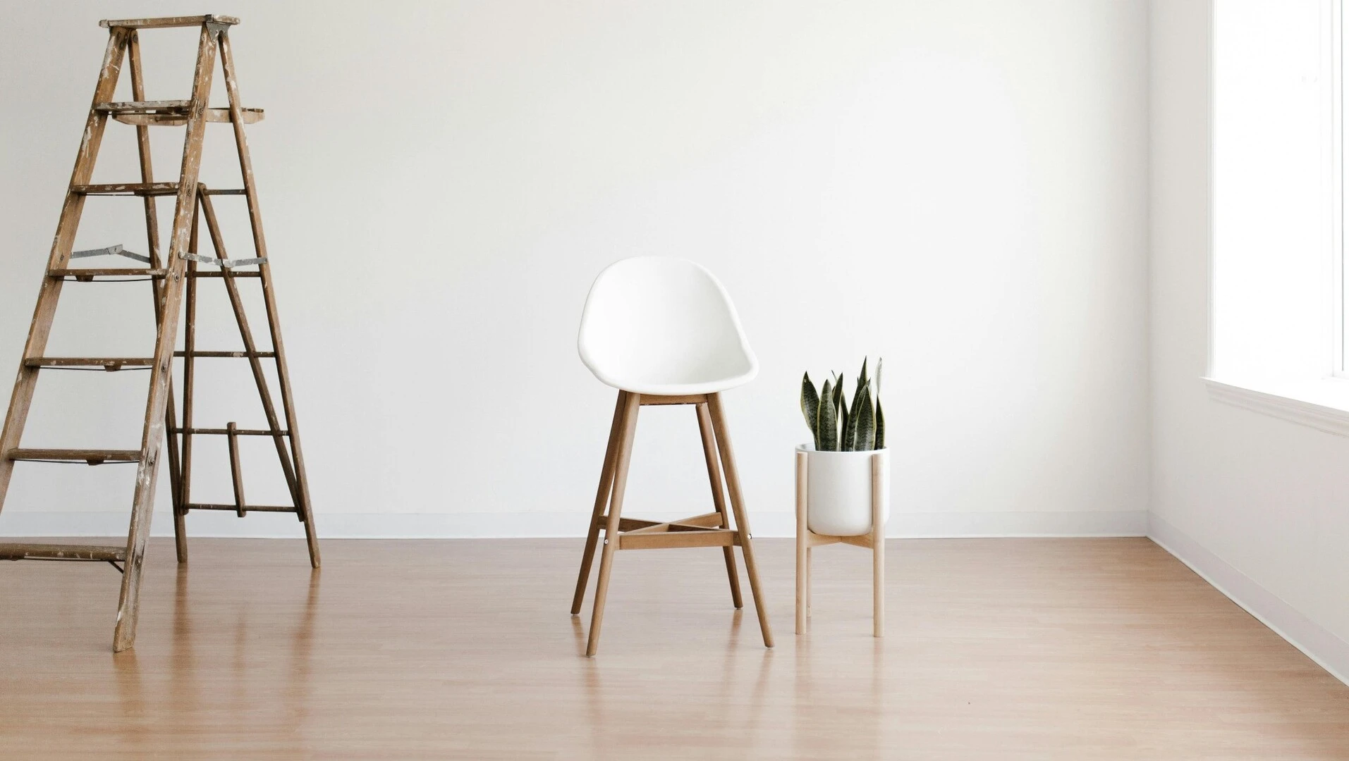 Pièce avec parquet avec une chaise et un pot sur des pieds en bois au centre